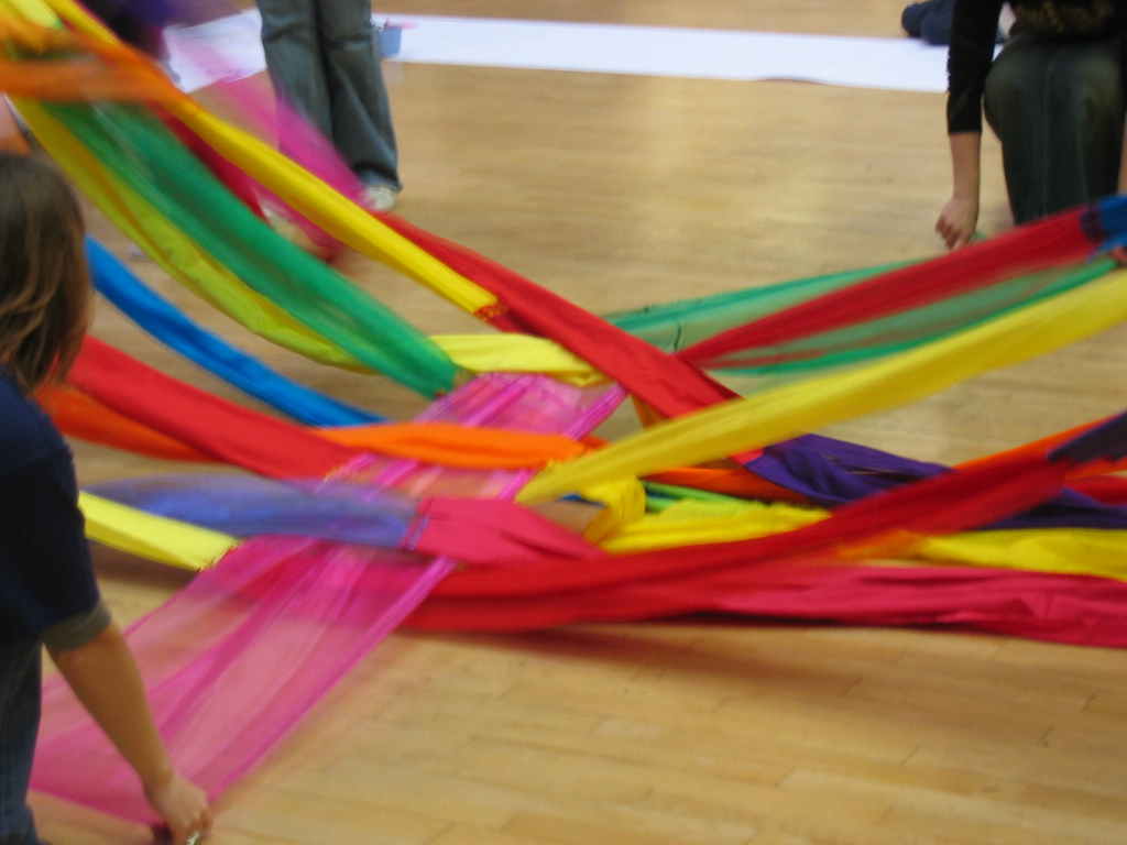 People performing a Giant Weave indoors and weaving fabric as they move